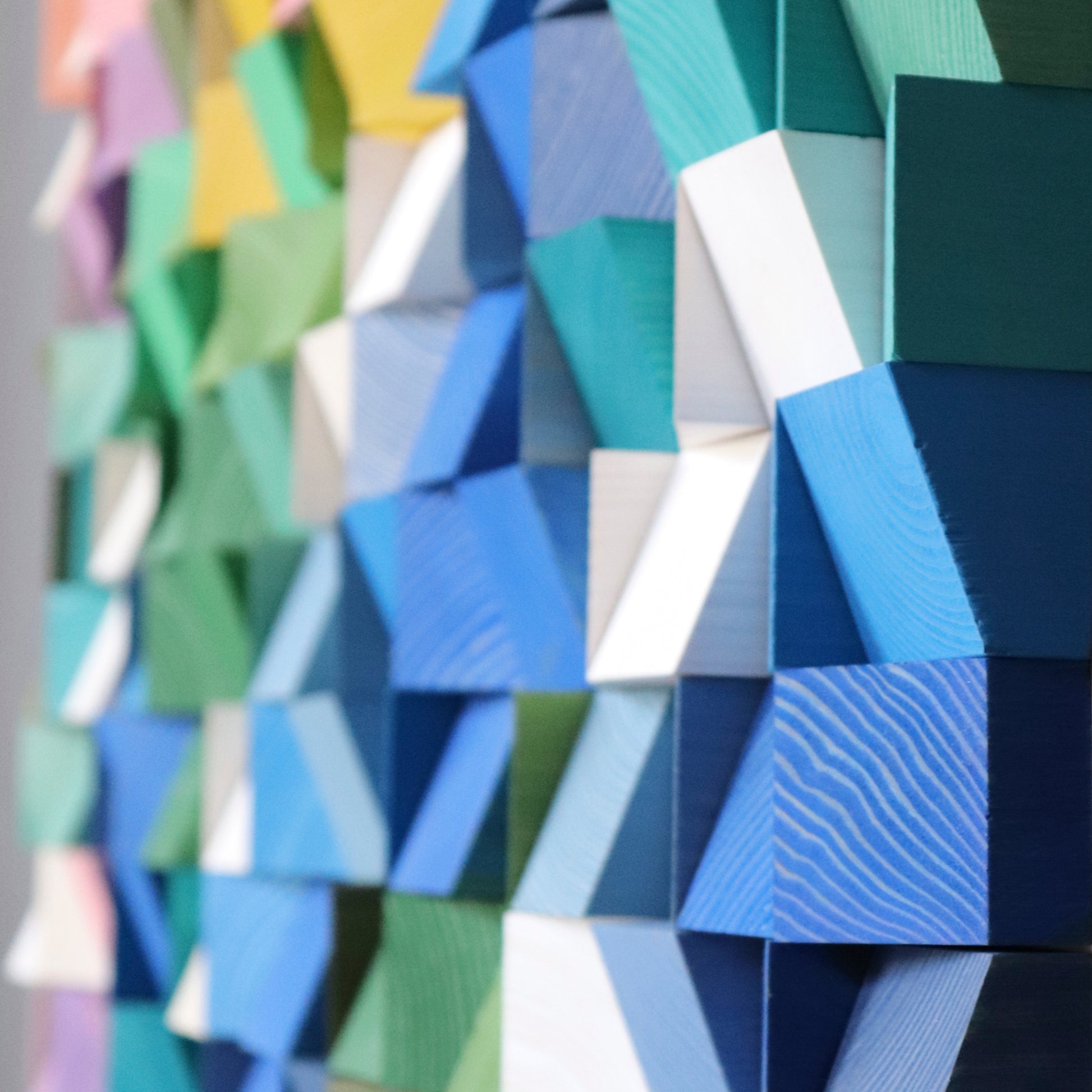 Detailed geometric wooden blocks painted in floral-inspired tones with texture and shadow.