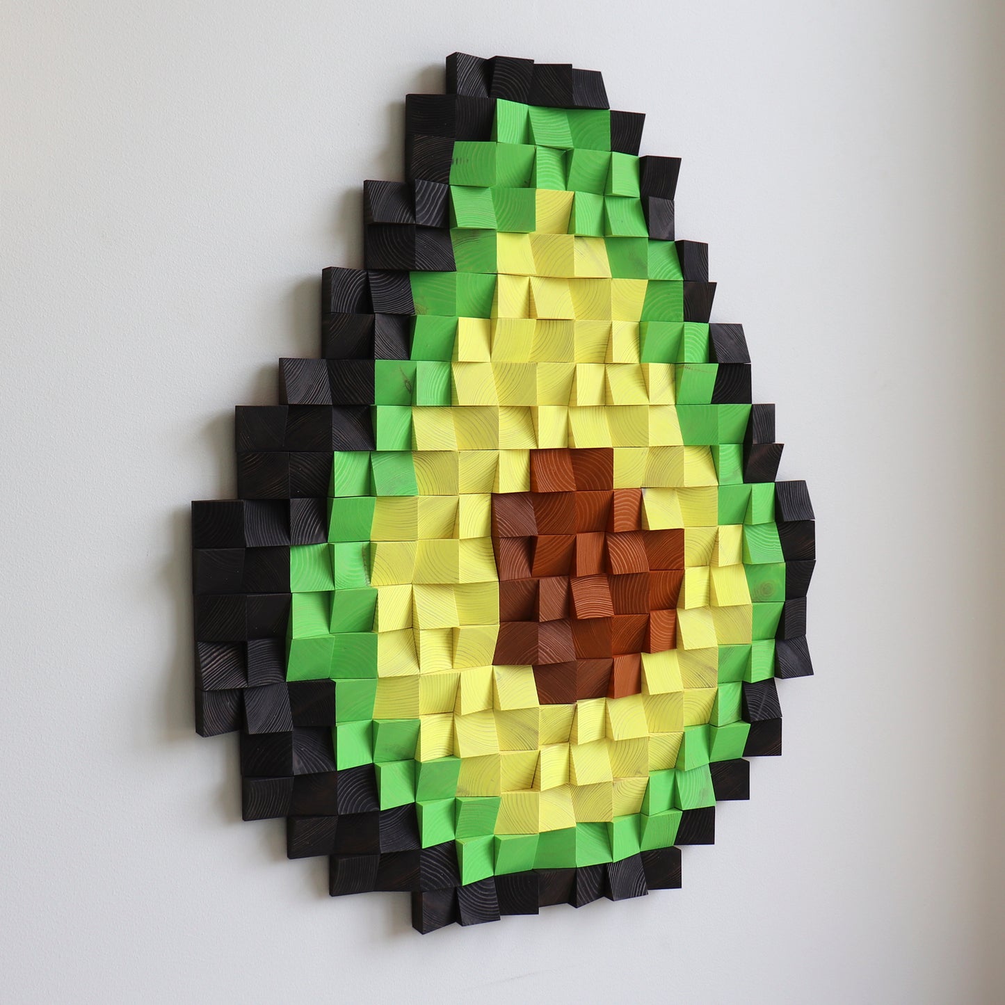 3D wooden avocado wall art made from carved wood blocks in green, yellow, and brown tones.