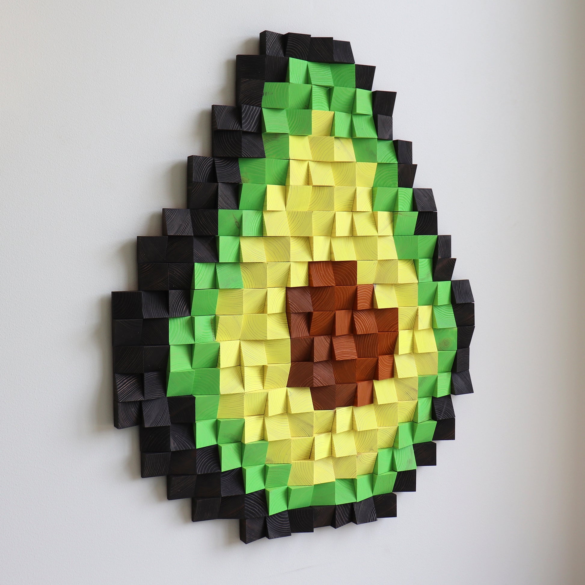 3D wooden avocado wall art made from carved wood blocks in green, yellow, and brown tones.