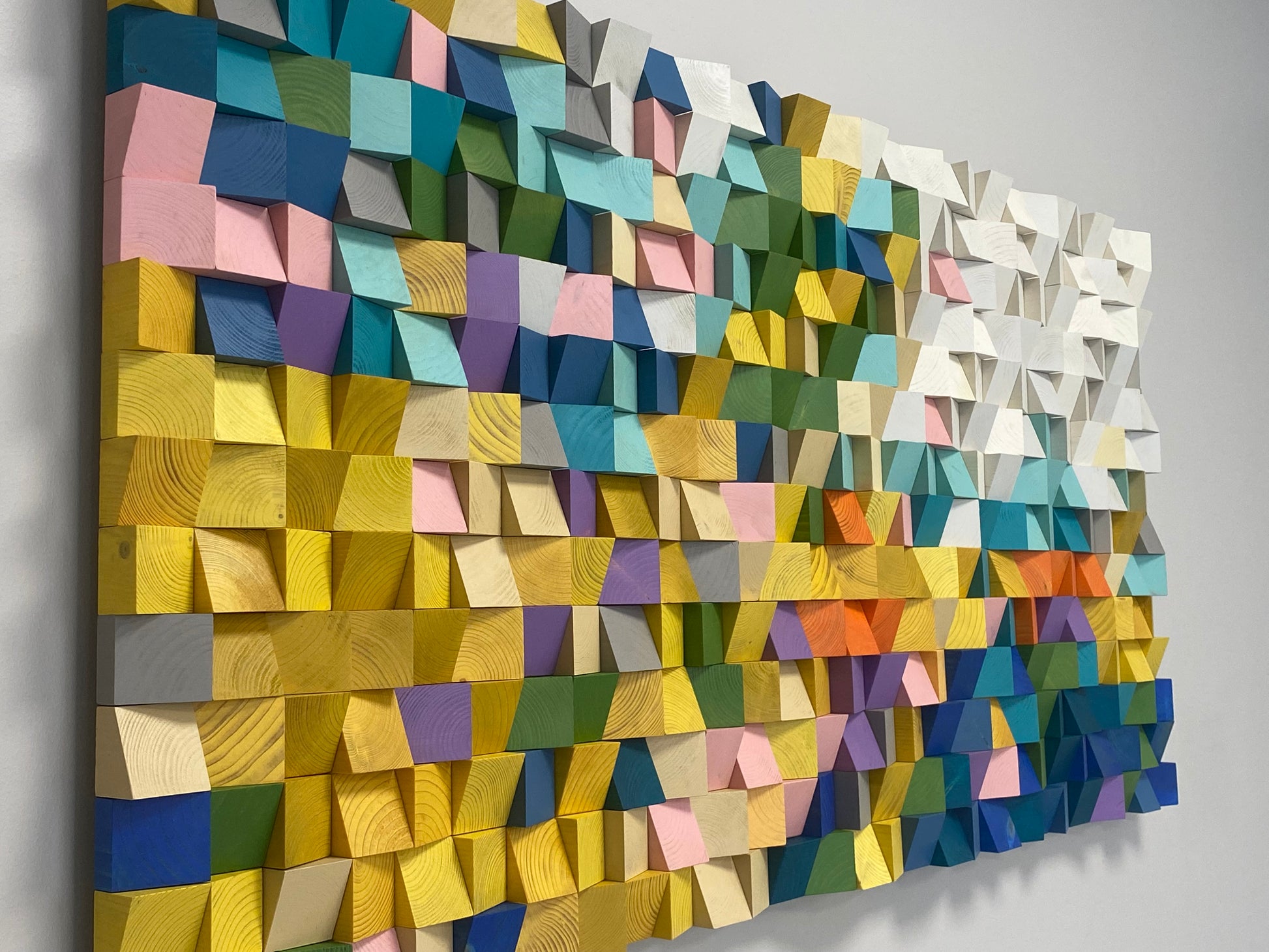 Colorful wooden mosaic wall panel made from sculpted geometric wood blocks.