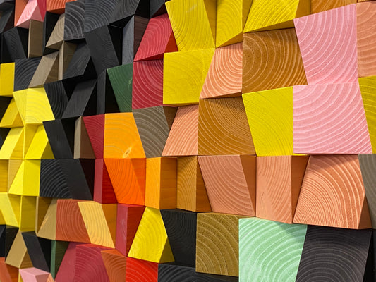 Handcrafted wooden wall art with bold red, yellow, and green hues creating a pixel-like design.