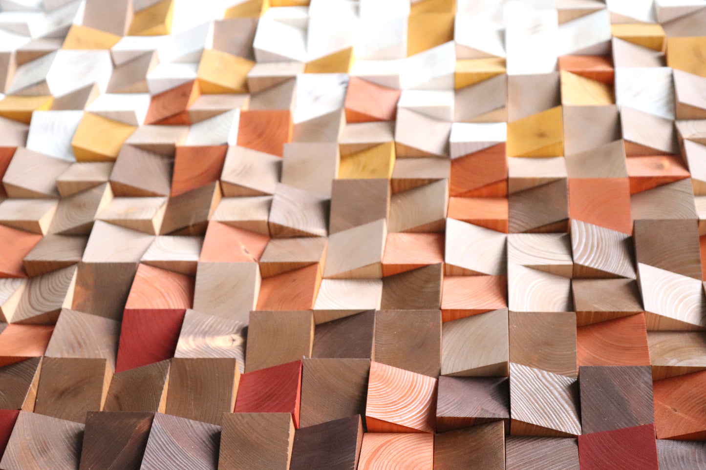 Detail close-up of faceted geometric blocks creating dynamic light and shadow on wood surface.