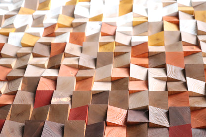 Detail close-up of faceted geometric blocks creating dynamic light and shadow on wood surface.