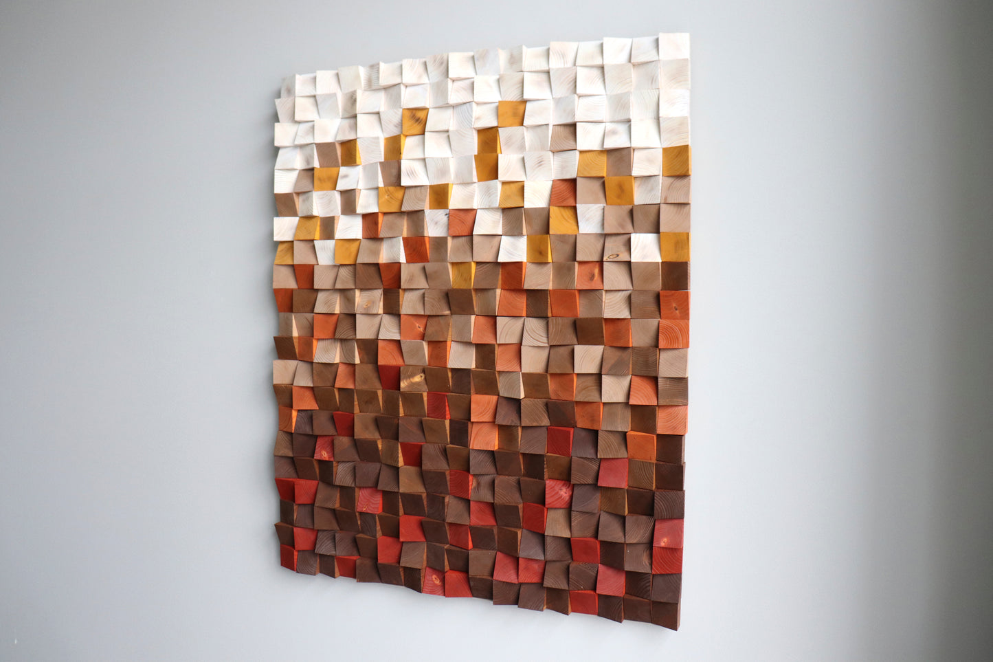 Right-angle view of modern geometric wood wall sculpture in red, beige, natural tones