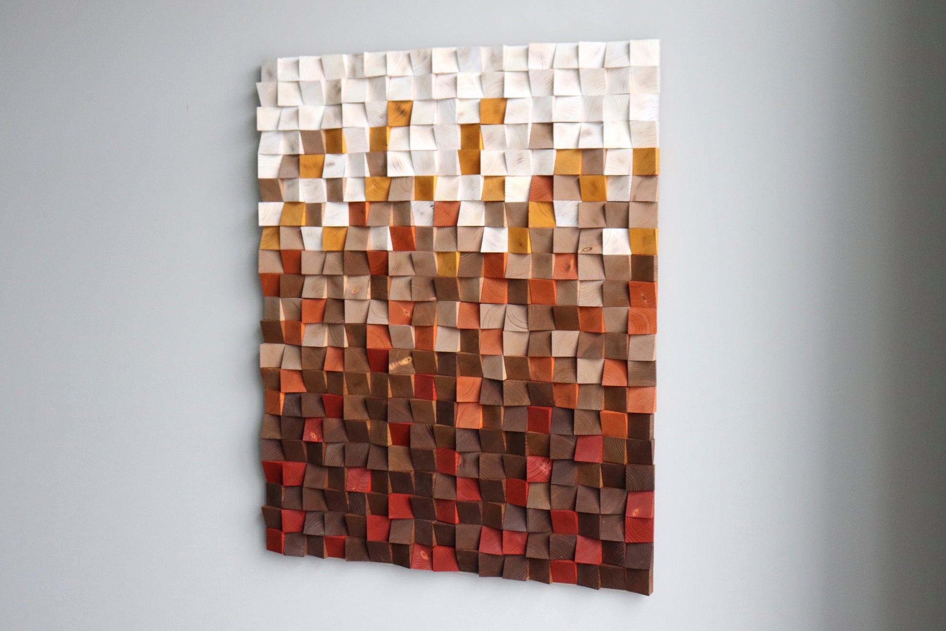 Right-angle portrait of modern geometric wood wall sculpture in red, beige and natural wood tones.