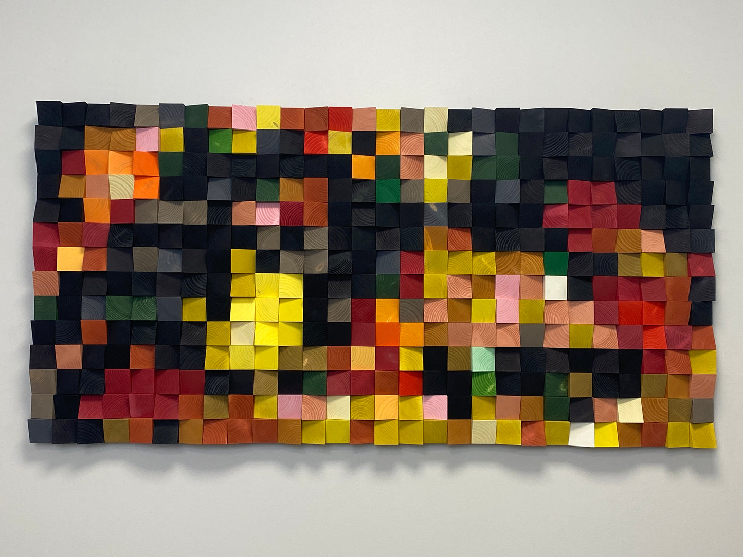 Modern acoustic wall decor featuring geometric wooden blocks in orange, red, and yellow tones.