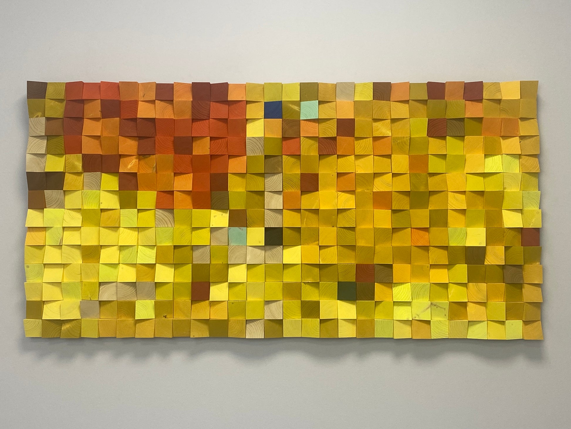 Multicolor acoustic wall panel made from sculpted wood blocks for sound diffusion and natural appeal.