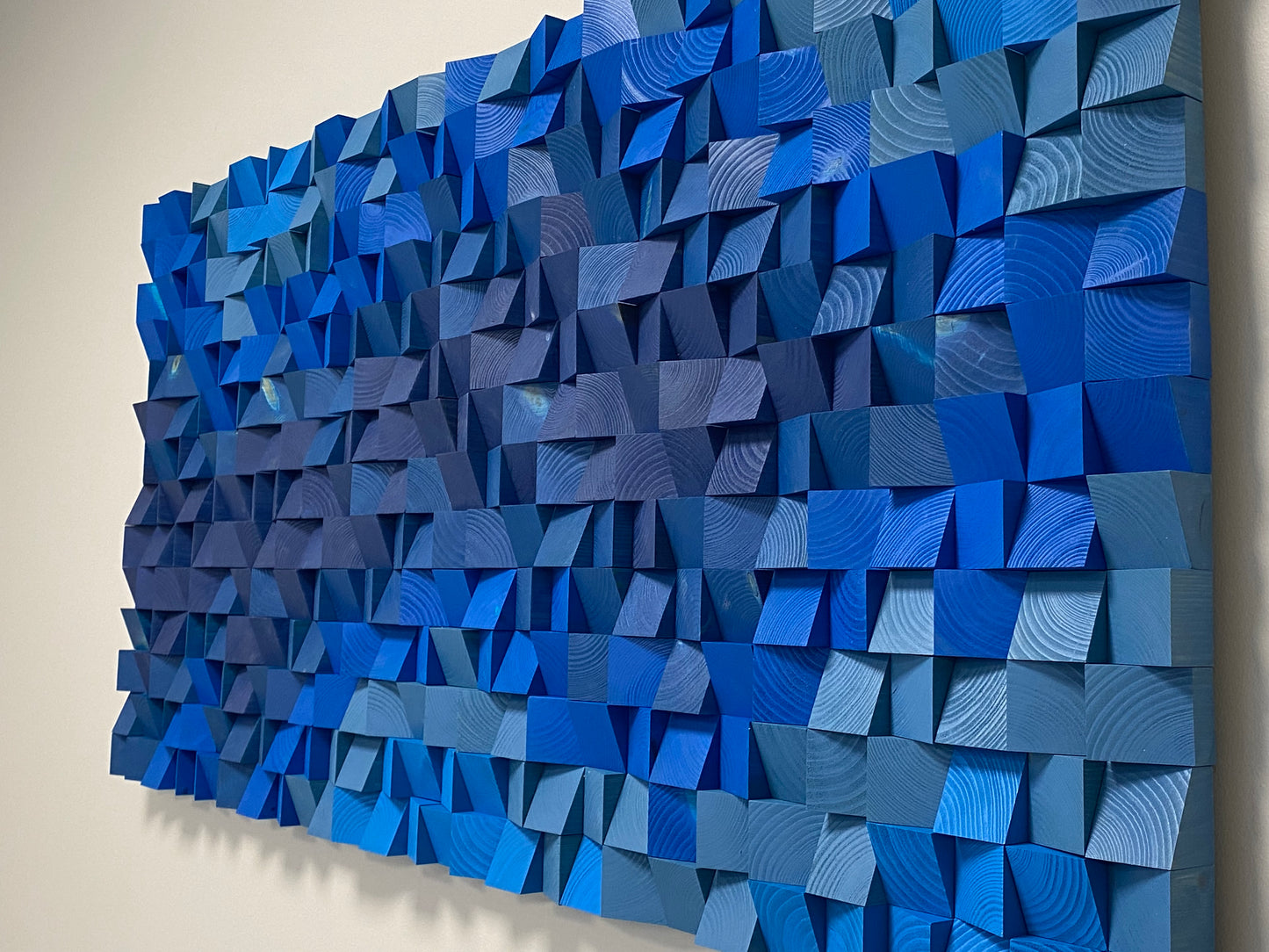 Detailed view of Deep Blue Ocean wooden acoustic panel showing wave-like blue texture and sound diffuser pattern.