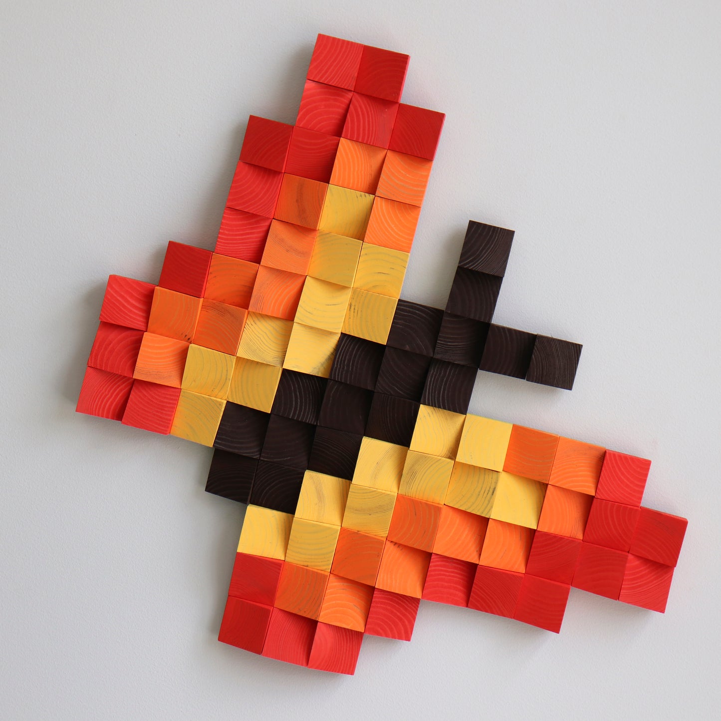 Pixel-inspired butterfly wall decoration made from red and orange carved wooden cubes.