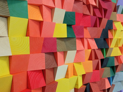 Handcrafted colorful wooden sound diffuser panel featuring bright geometric blocks in rainbow hues.