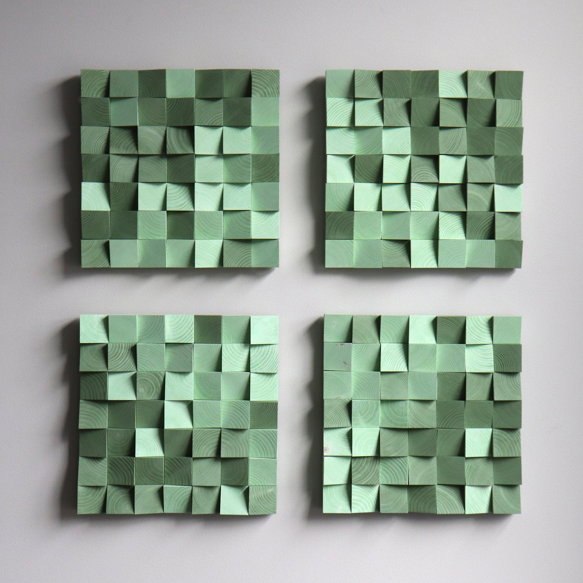 Green wooden art panel with sculpted 3D blocks and warm color palette.