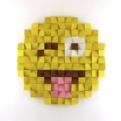 Winking face with tongue emoji wall art made from yellow, white, brown, and pink wooden cubes in a raised 3D pixel design.