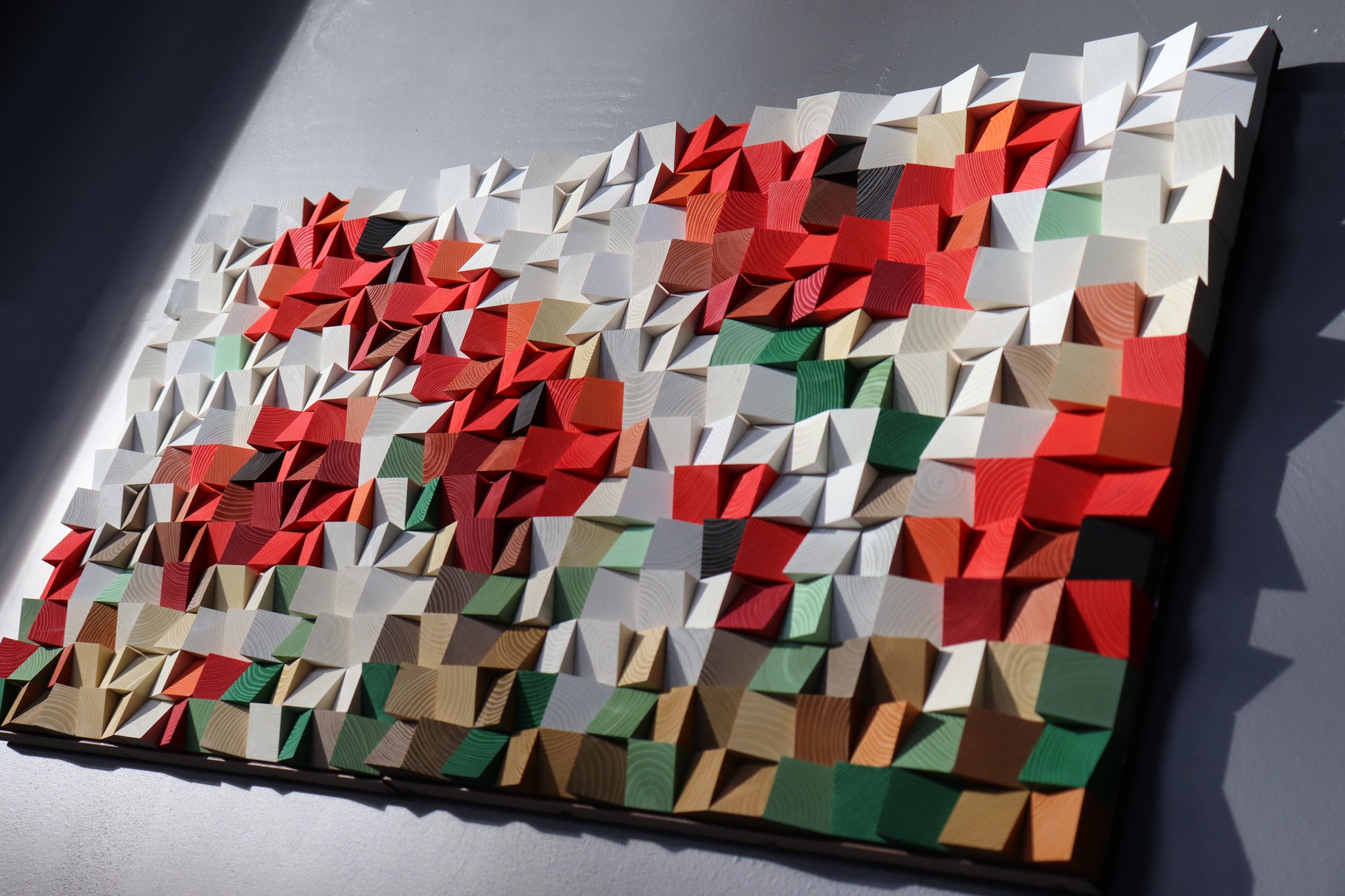 Unique handmade wood wall art combining natural and painted blocks for a modern artistic effect.