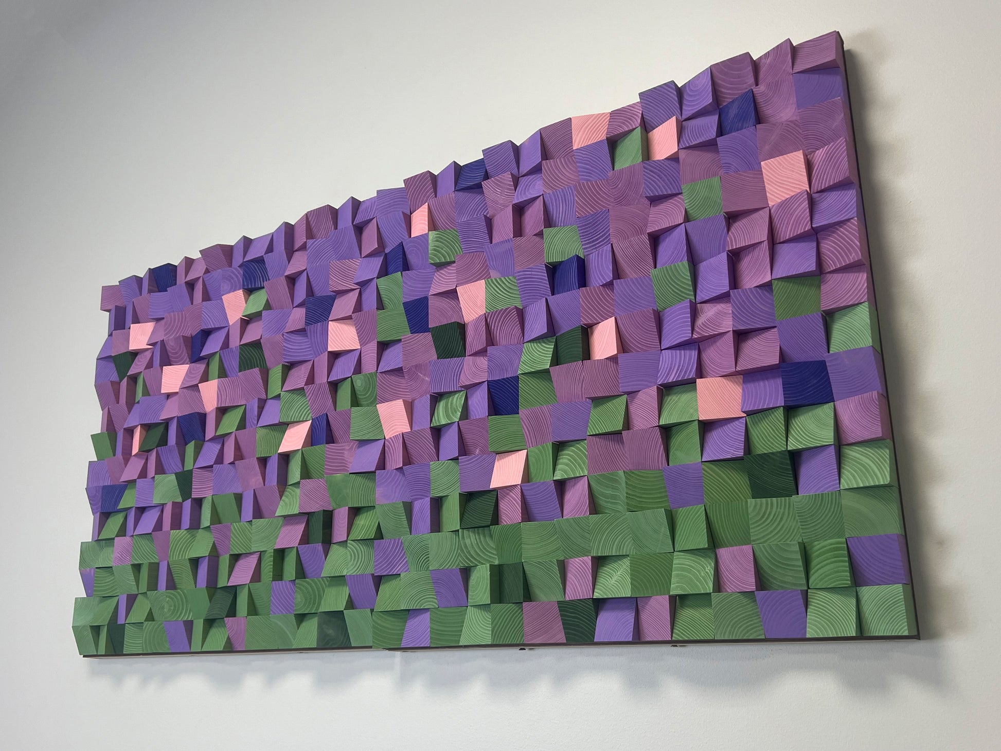 Geometric wood wall panel with lavender, green, and pink tones creating a floral-inspired pattern.