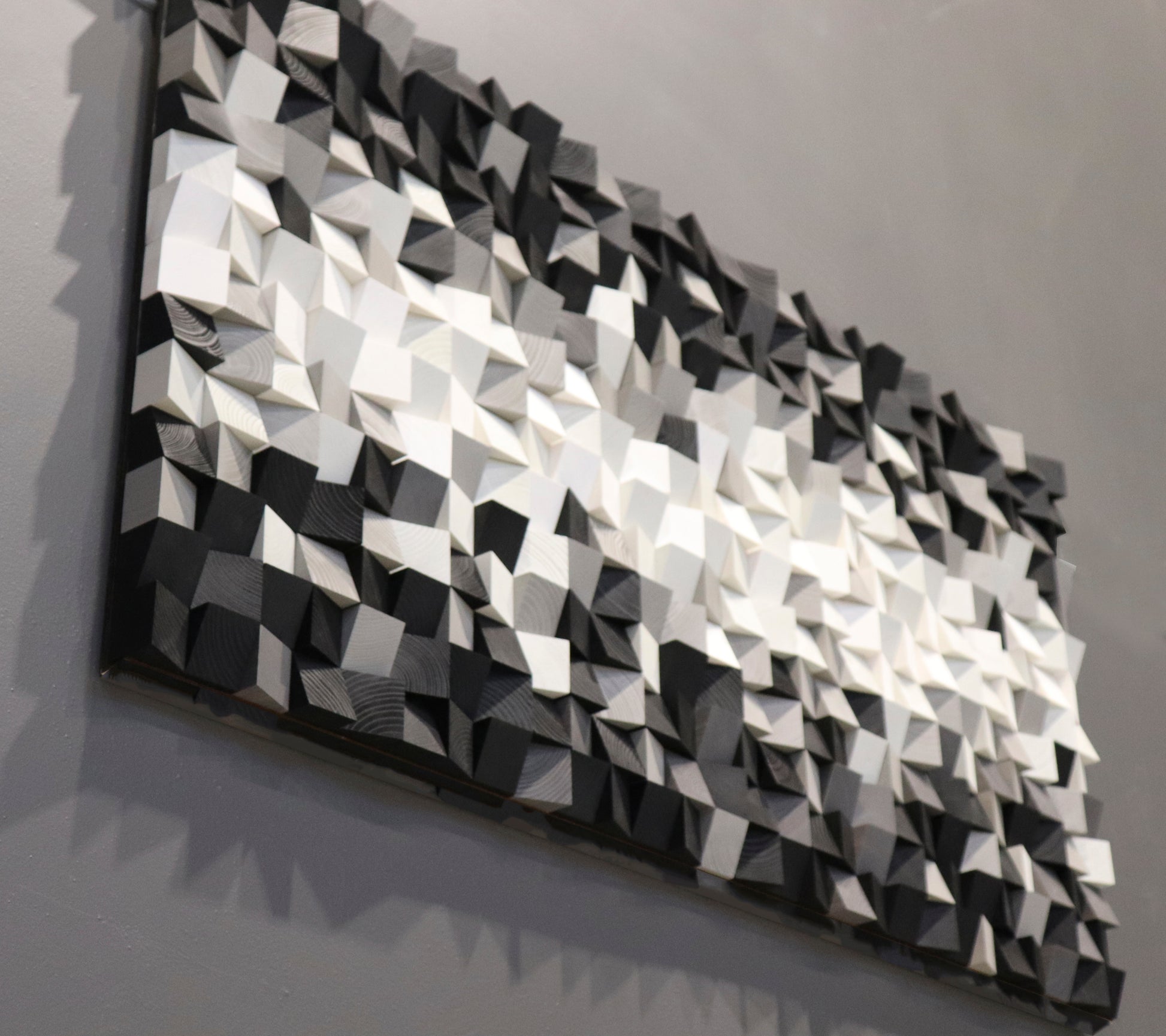 Geometric modern art wood wall piece made from hand-carved blocks in grayscale shades.