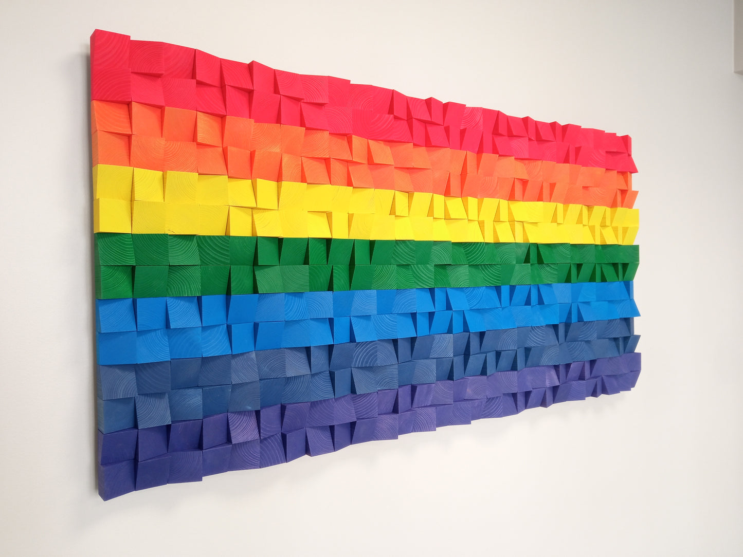 Wooden sound diffuser wall art with colorful layers enhancing both acoustics and visual design.