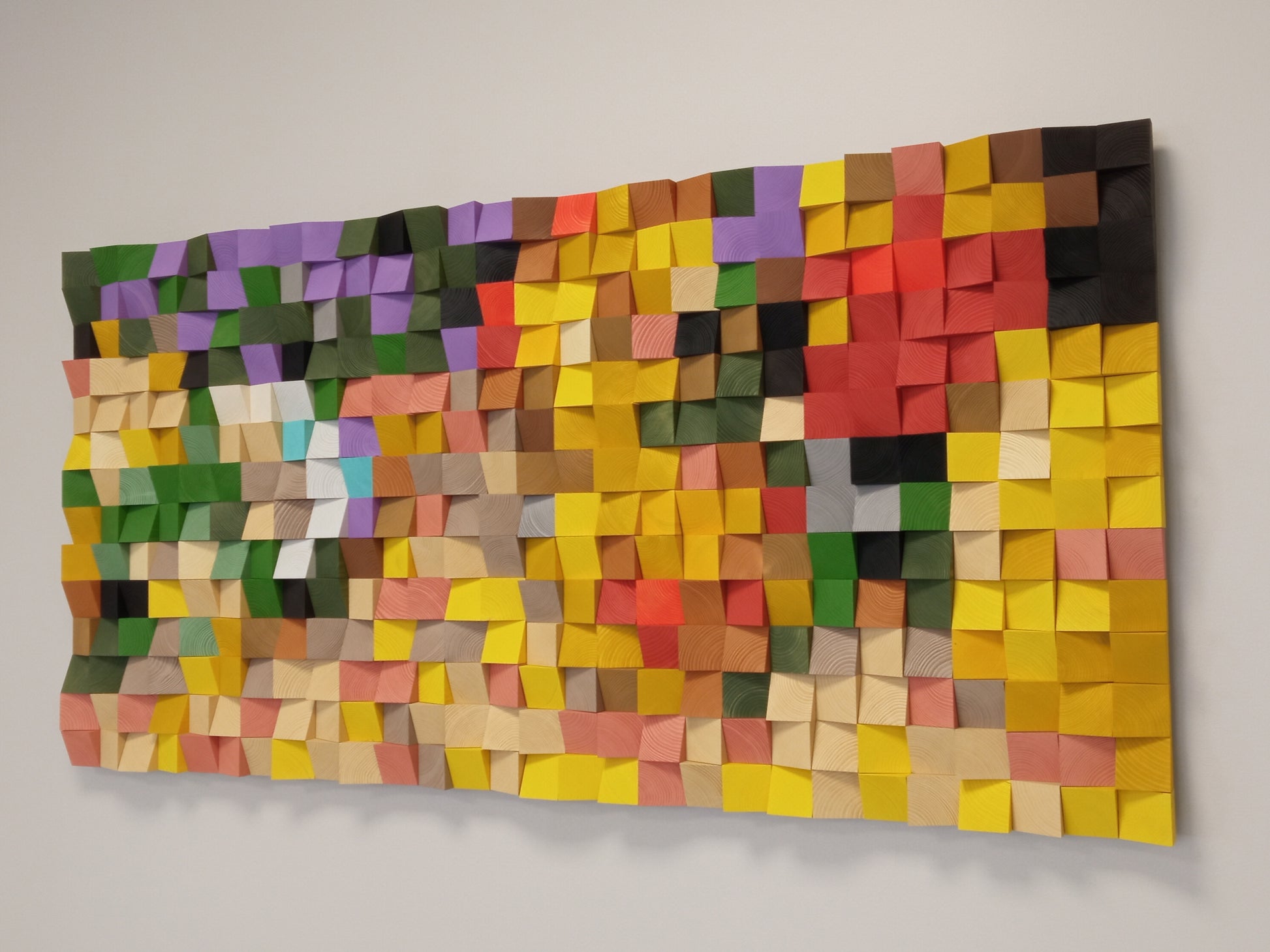 Wooden sound diffuser and acoustic art piece in rich autumn shades of red, yellow, and green.